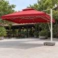 Dù tán vuông đỏ có diềm, trụ trắng bên phải và đế thấp trước khu bàn ghế được dọn xa