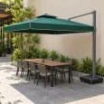 Dù tán chữ nhật xanh có diềm, trụ bên phải che bàn dài cạnh tường và lối đi