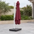 Tán dù đỏ xếp thành nếp dọc bên trụ trắng, bộ đỡ đã thu và đế vuông thấp trên sân khô
