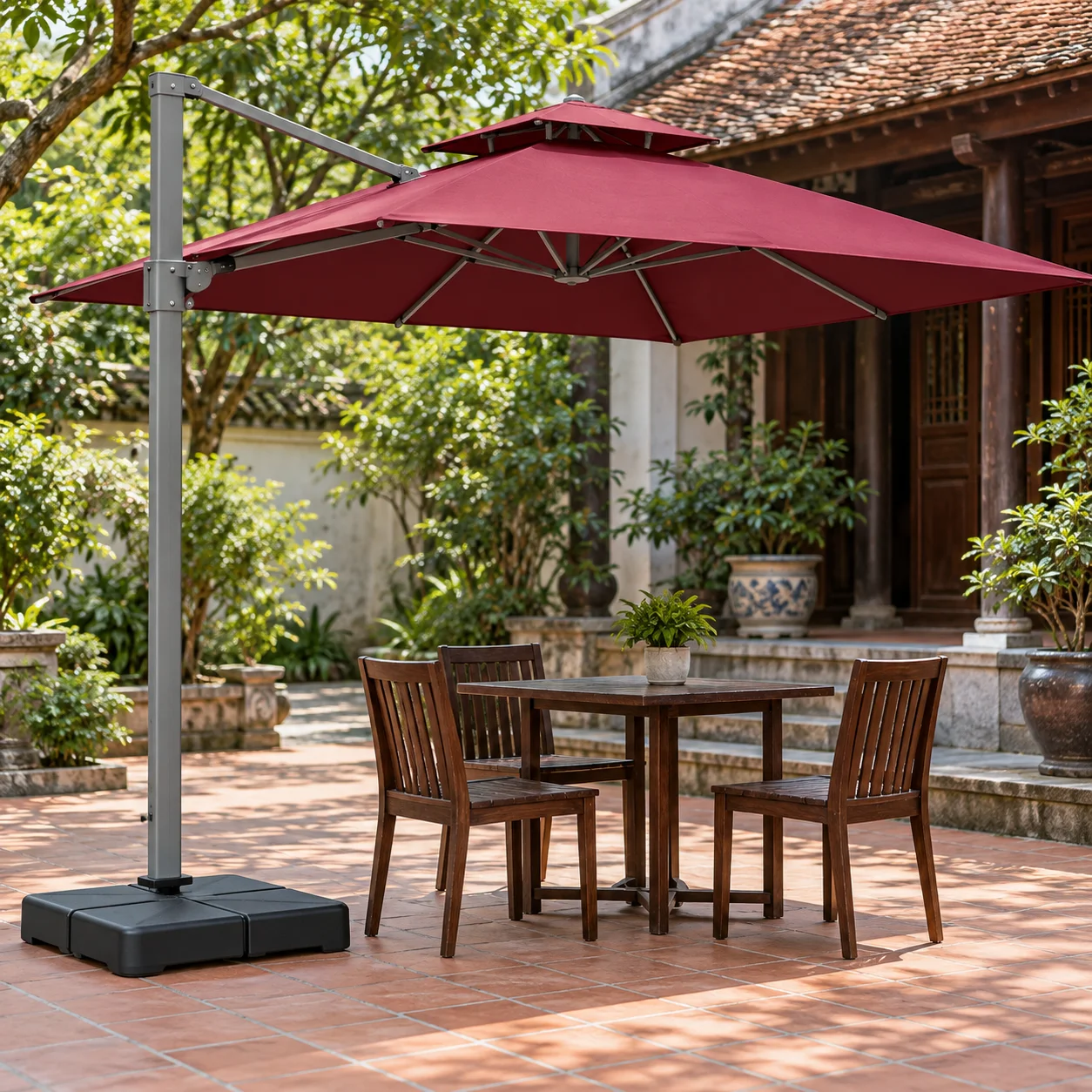 Đối chiếu hình tán vuông và bộ đỡ trước chọn mẫu Dù lệch tâm tán vuông đỏ đô hai tầng, trụ xám bên trái và đế thấp cạnh bàn gỗ