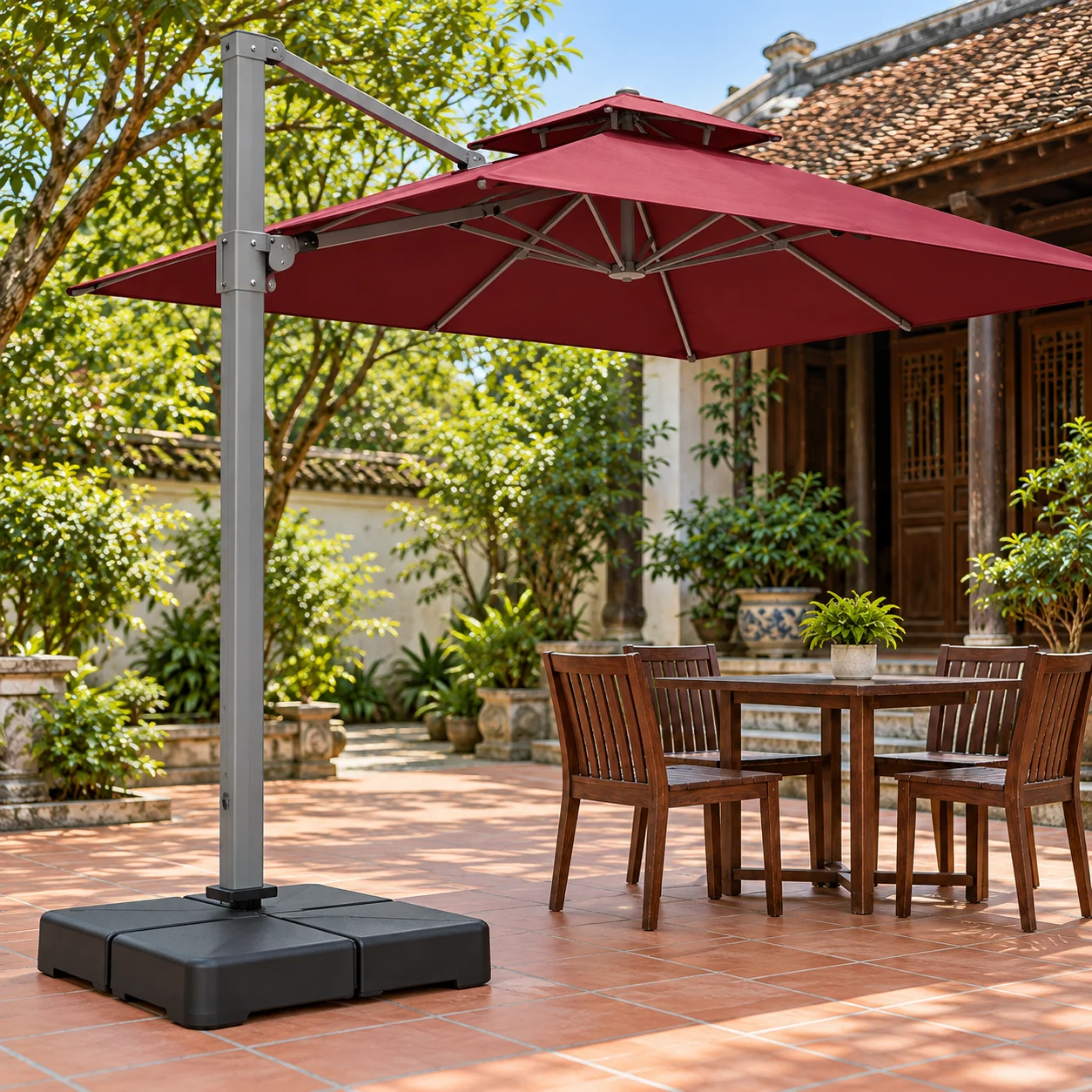Kiểm tra phần đế và khoảng trống cạnh bàn Cận cảnh bộ đế thấp và trụ bên của dù vuông đỏ đô cạnh bàn gỗ trên sân lát gạch