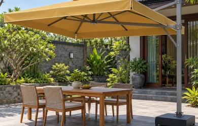 Minh họa dù lệch tâm tán chữ nhật vàng có viền sáng, trụ bên phải và đế thấp cạnh bàn ăn ngoài trời