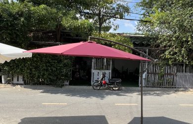 Ô lệch tâm tán đỏ với trụ bên cạnh và chân đế trên sân