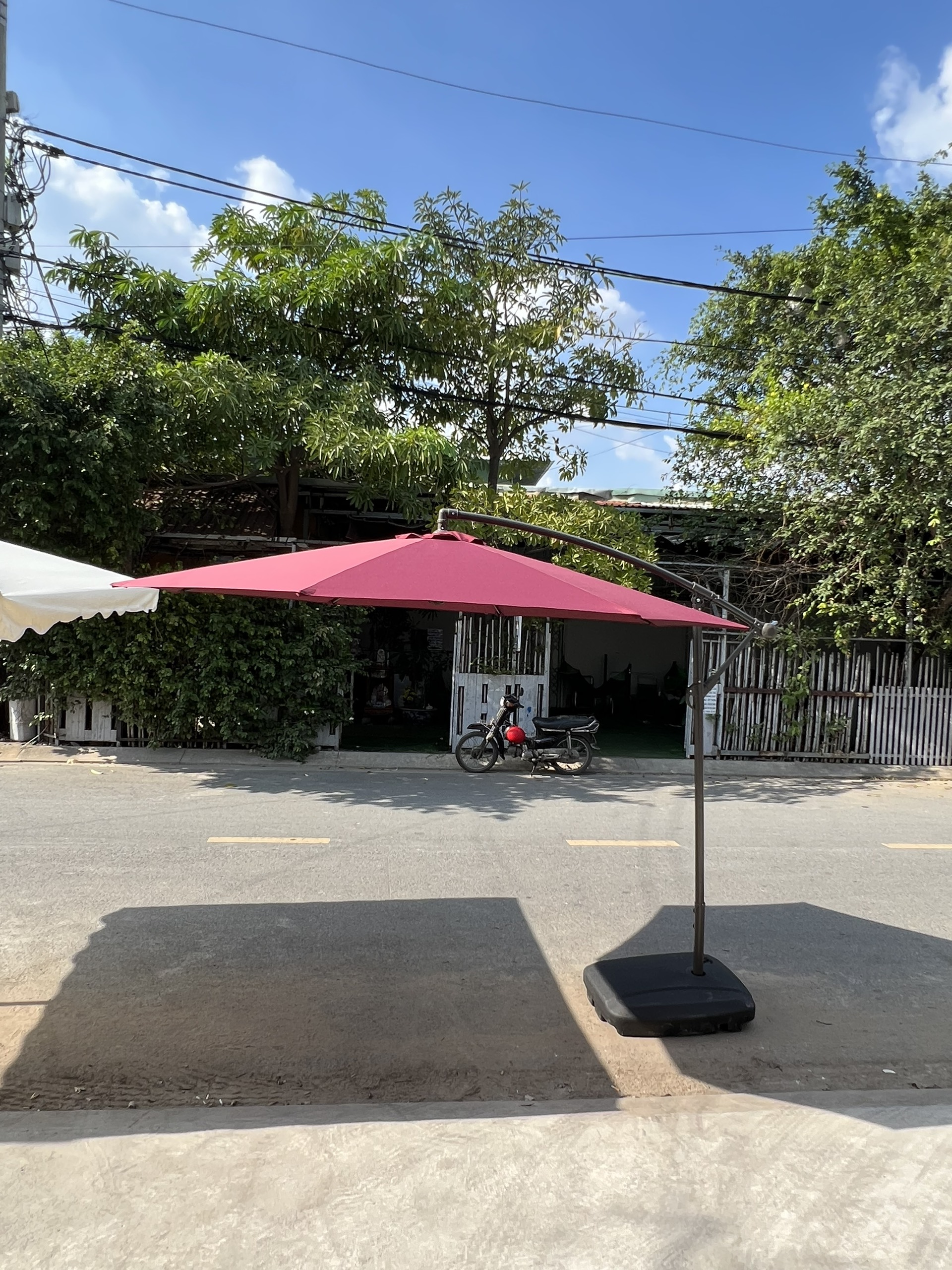 Ô lệch tâm tán đỏ với trụ bên cạnh và chân đế trên sân Ô lệch tâm tán đỏ với trụ bên cạnh và chân đế trên sân